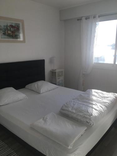 - une chambre avec un lit doté de draps blancs et une fenêtre dans l'établissement Vue panoramique PORT et OCEAN, à Saint-Gilles-Croix-de-Vie