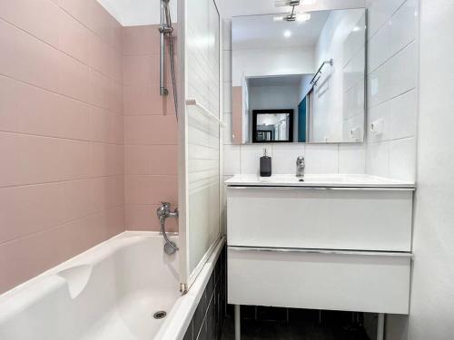 La salle de bains est pourvue d'une baignoire, d'un lavabo et d'un miroir. dans l'établissement Shining Sun Flat Lyon Caluire et parkings, à Caluire-et-Cuire