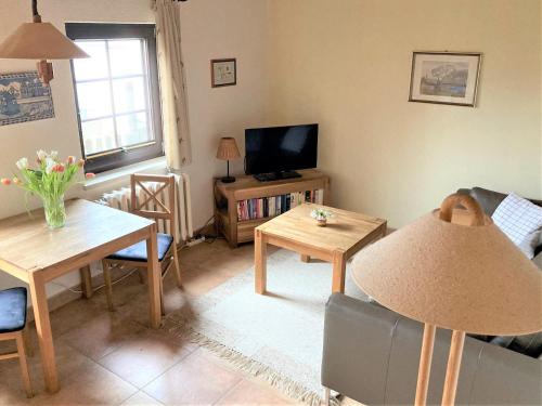 a living room with a table and a tv at Töpferweg 06 Ferienwohnung Tine in Ahrenshoop