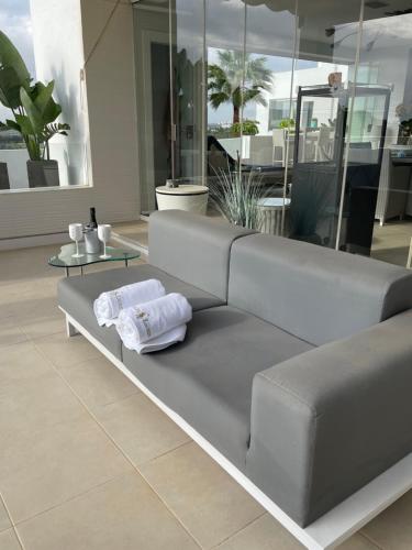 een grijze bank in een kamer met 2 handdoeken bij Estepona Luxe top appartement in finca de cortesin d38 in Estepona