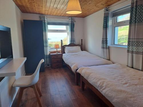 a bedroom with two beds and a tv and a chair at Blaneys Coastal Cottage in Mountcharles