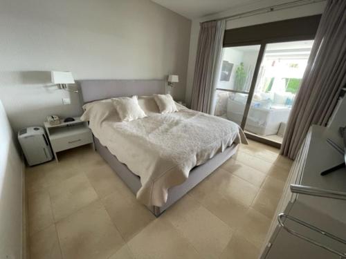een witte slaapkamer met een bed en een raam bij Estepona Luxe top appartement in finca de cortesin d38 in Estepona