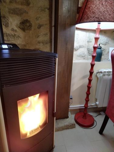a fire burns in a fireplace next to a lamp at Casa Quimera in Gilgarcía