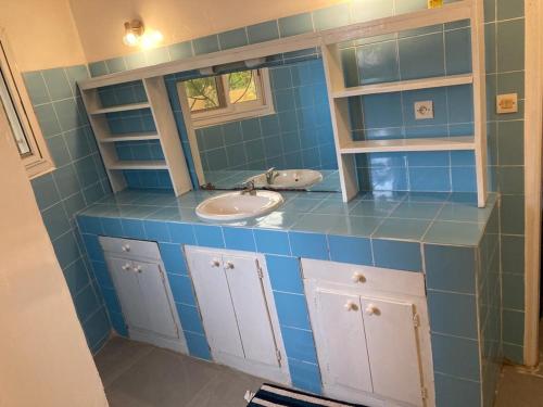 Baño de azulejos azules con lavabo y espejo en Villa avec piscine à Ndangane, en Ndangane