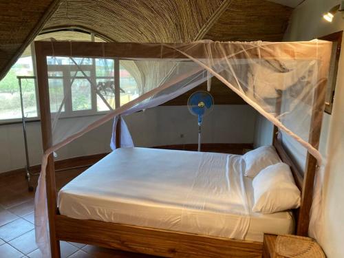 Villa avec piscine à Ndangane في Ndangane: غرفة نوم مع سرير المظلة مع ملاءات بيضاء