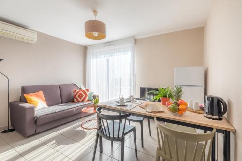 een woonkamer met een bank en een tafel met stoelen bij Appart'City Confort Toulouse Aéroport Cornebarrieu in Cornebarrieu