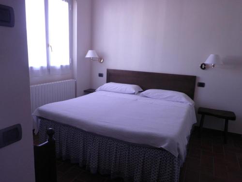 1 dormitorio con 1 cama con sábanas blancas y ventana en Locanda Verbena, en Stresa