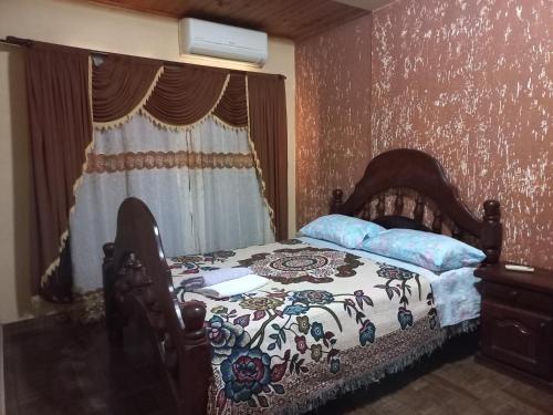 um quarto com uma cama com um cobertor florido e uma janela em Salto dos hermanas em Puerto Iguazú