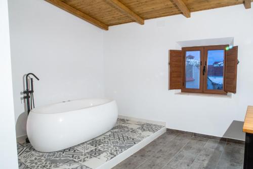- une salle de bains blanche pourvue d'une baignoire. dans l'établissement El Pelaor, à Benquerencia