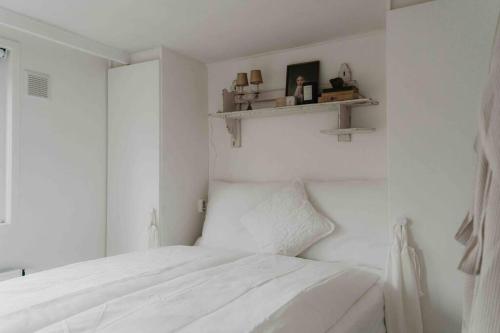 een witte slaapkamer met een bed en een raam bij Brocante Holiday Home aan de bosrand! in Ermelo