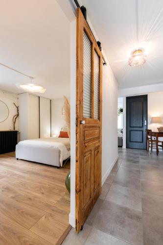 - une chambre avec un lit et une porte en bois dans l'établissement L'annexe Landaise, à Saint-Martin-de-Seignanx