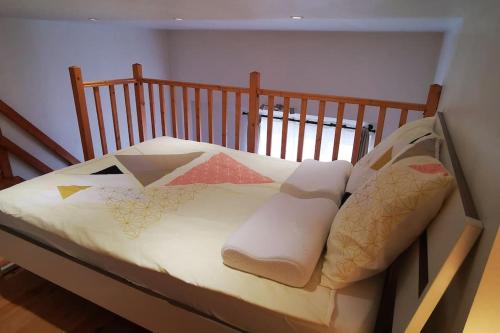 - un lit avec un cadre en bois et des oreillers dans l'établissement Studio privé/ centre-ville/ proche du parc Walibi, à Les Avenières