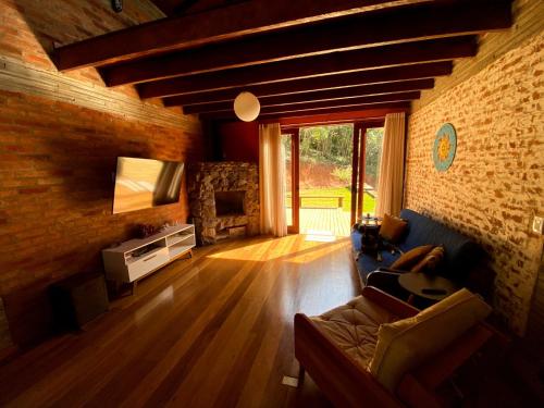 a living room with a couch and a tv at Casa Cacau Boutique B&B - Sítio Salamandra Vale do Matutu in Aiuruoca