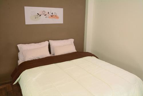 a bedroom with a white bed with two pillows at Villa Apart Center in Villa Constitución
