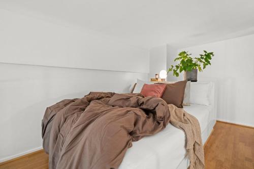 a white bed with a blanket and pillows on it at Art Loft in downtown Oslo with Home Cinema in Oslo