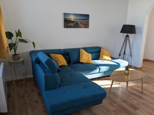 um sofá azul com almofadas amarelas numa sala de estar em l'Opale Break em Calais