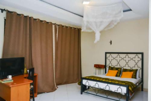 Dormitorio con cama, escritorio y TV en Naalya Motel en Kampala