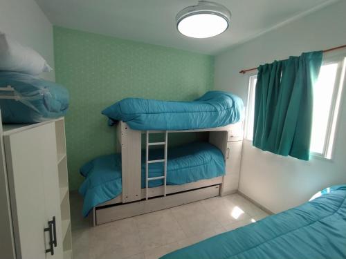 Habitación con 3 literas y almohadas azules. en sambernardo, en San Bernardo