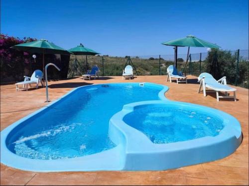 uma grande piscina com cadeiras e guarda-sóis em El Rincón de los Albaricoques em Níjar