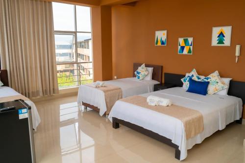 a hotel room with two beds and a balcony at Tropical City in Tarapoto