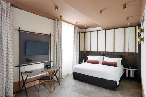 um quarto com uma cama, uma secretária e uma televisão em Palazzo Velabro, a Member of Design Hotels em Roma