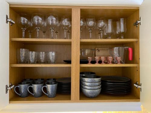 a cabinet filled with glasses and plates and bowls at Llandudno Boutique style seaside retreat with stunning views in Llandrillo-yn-Rhôs