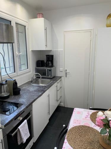 une petite cuisine avec des armoires blanches et un évier dans l'établissement Charmant appartement - PARIS 18, à Paris