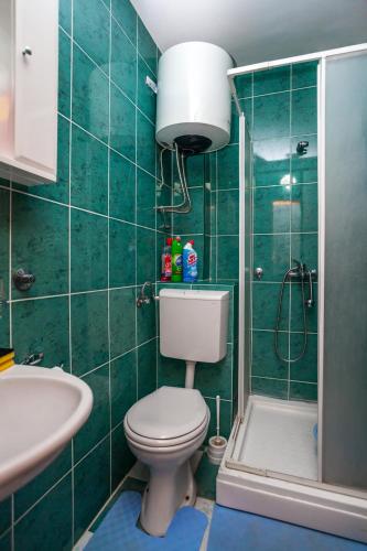 a green tiled bathroom with a toilet and a shower at Apartments Marko in Tivat