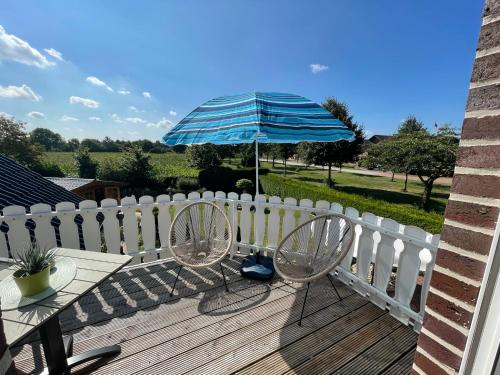 a patio with two chairs and an umbrella on a deck at Ferienzimmer Claudia in Surwold
