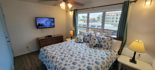 a bedroom with a bed and a tv and a window at Gulfview I #213 in South Padre Island