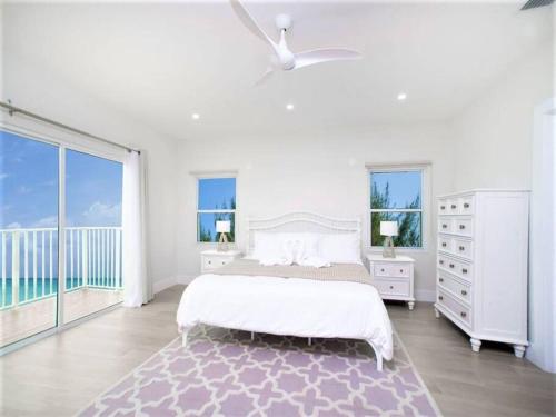 a white bedroom with a bed and a balcony at Azure Breeze # 6 in North Side