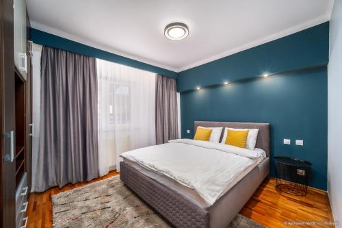 a bedroom with a bed with a blue wall at Apartament Nordic in Gura Humorului