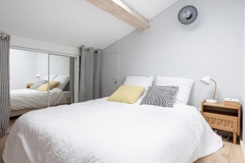 une chambre blanche avec un grand lit et un miroir dans l'établissement Appartement sous les toits 5 min du palais à pied, à Cannes