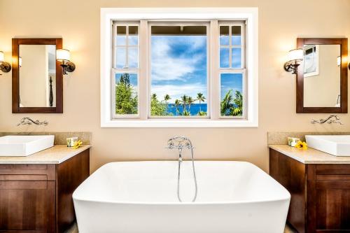 La salle de bains est pourvue d'une baignoire blanche, de deux lavabos et d'une fenêtre. dans l'établissement Golf Green, à Kailua-Kona
