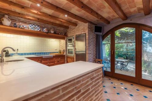 a kitchen with a counter and a large window at HHBCN Villa El Castell in El Bruc