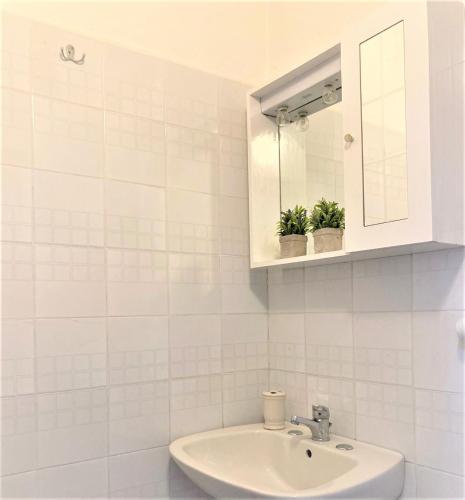 W białej łazience znajduje się umywalka i lustro. w obiekcie A due passi dalla Stazione Centrale di Milano w Mediolanie