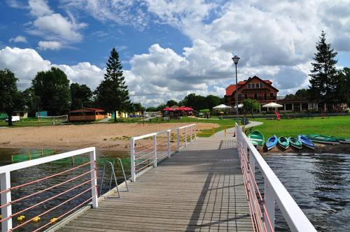 a wooden dock with boats on a beach and a house at Hotel Słoneczny Brzeg in Biskupiec