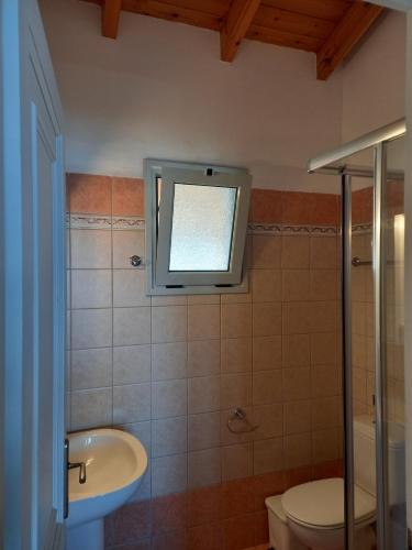 a bathroom with a toilet and a sink and a window at Lidovois House in Pelekas