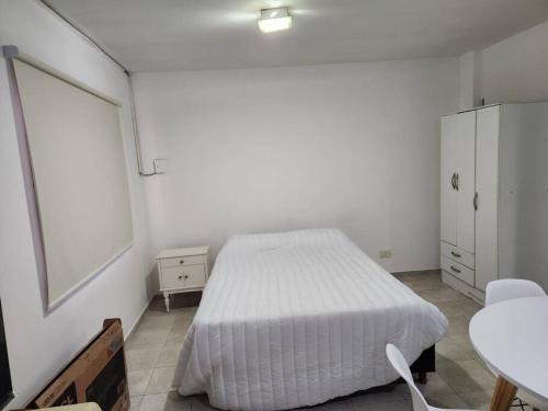 een witte slaapkamer met een bed en een tafel bij San Luis suits in Mendoza