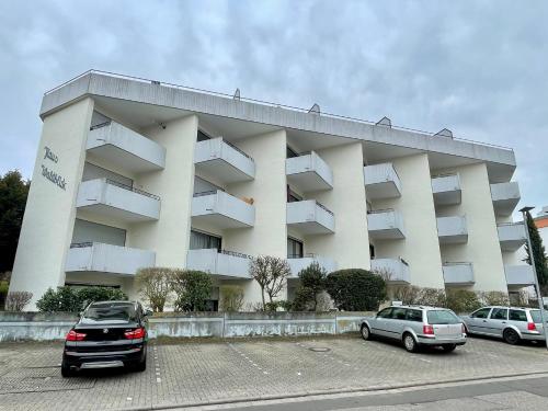 ein großes weißes Gebäude mit Autos auf einem Parkplatz in der Unterkunft Ferienwohnung David im Haus Waldblick - Bad Bergzabern in Bad Bergzabern