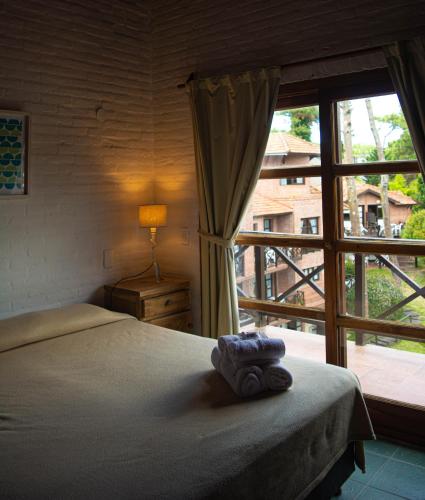 カリロにあるCariló Paradise Apart Hotel & Spaのベッドと大きな窓のある寝室