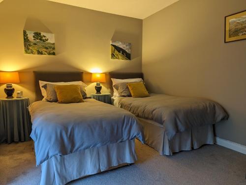 two beds in a room with two lamps at The Stables at Lorum Old Rectory in Bagenalstown