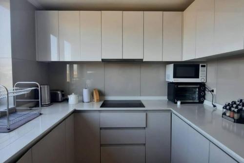 a white kitchen with white cabinets and a microwave at Departamento frente al mar in Coquimbo