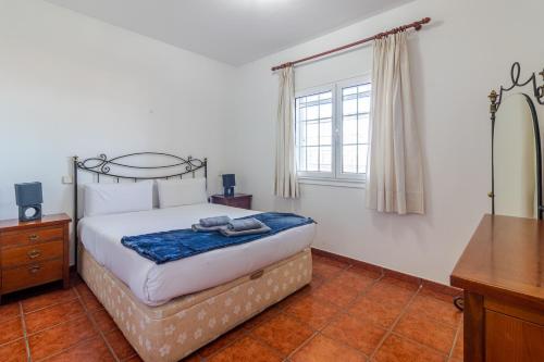 a bedroom with a bed and a dresser and a window at Flatguest Villa Mayca in Santa Brígida