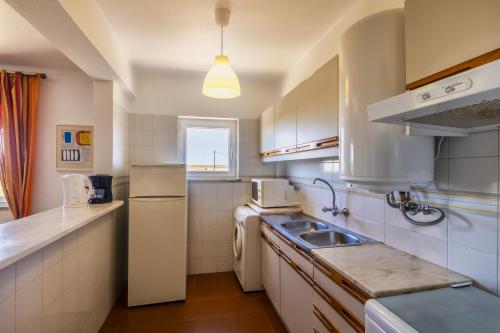 uma cozinha com um lavatório e um frigorífico em Branco em Sagres