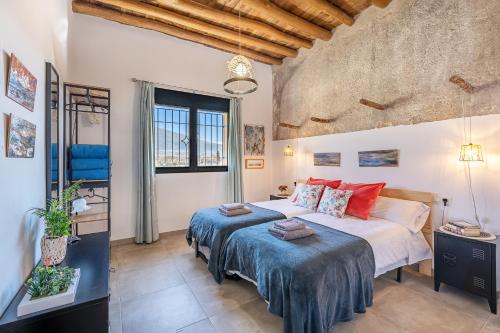 een slaapkamer met een groot bed met blauwe lakens en rode kussens bij La Criba - Casa rural Eralta in Dúrcal