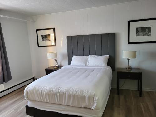 ein Schlafzimmer mit einem großen weißen Bett mit zwei Nachttischen in der Unterkunft Hotel Sigma in Val-dʼOr