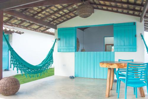 a room with a table and chairs and a hammock at CHALÉ NAMORADA PATACHO in Pôrto de Pedras