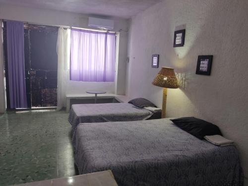 Cette chambre comprend 2 lits et une fenêtre. dans l'établissement Hostal Maruvillas, à Mérida