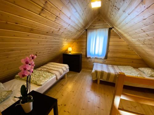 a attic room with two beds and a window at Domki z bali Deluxe in Jarosławiec